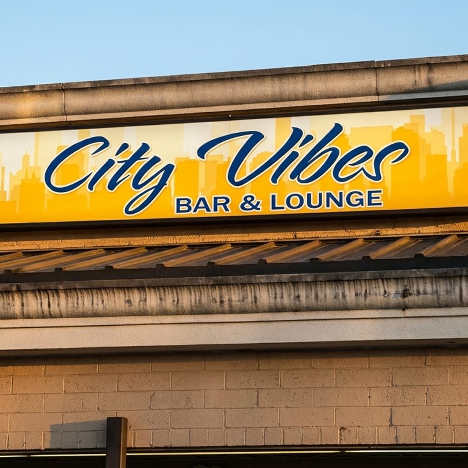 A yellow and blue "City Vibes Bar & Lounge" sign on a brick building under a clear sky.